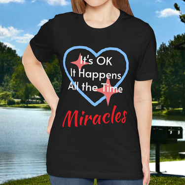 Soft, breathable Bella+Canvas t-shirt made from preshrunk cotton with “Miracles Happen” design message, “It’s OK. It Happens All the Time – Miracles,” inspirational shirt encouraging intimacy with God that produces everyday miracles, woman wearing black t-shirt